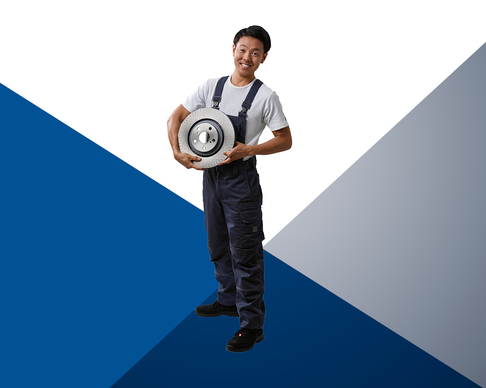 Car mechanic holding a brake discs in his arms